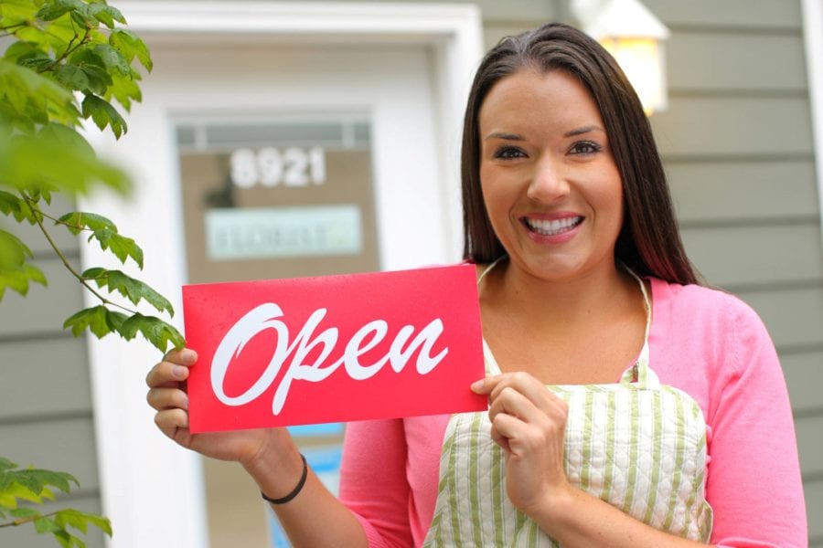 Small business owner with “open” sign