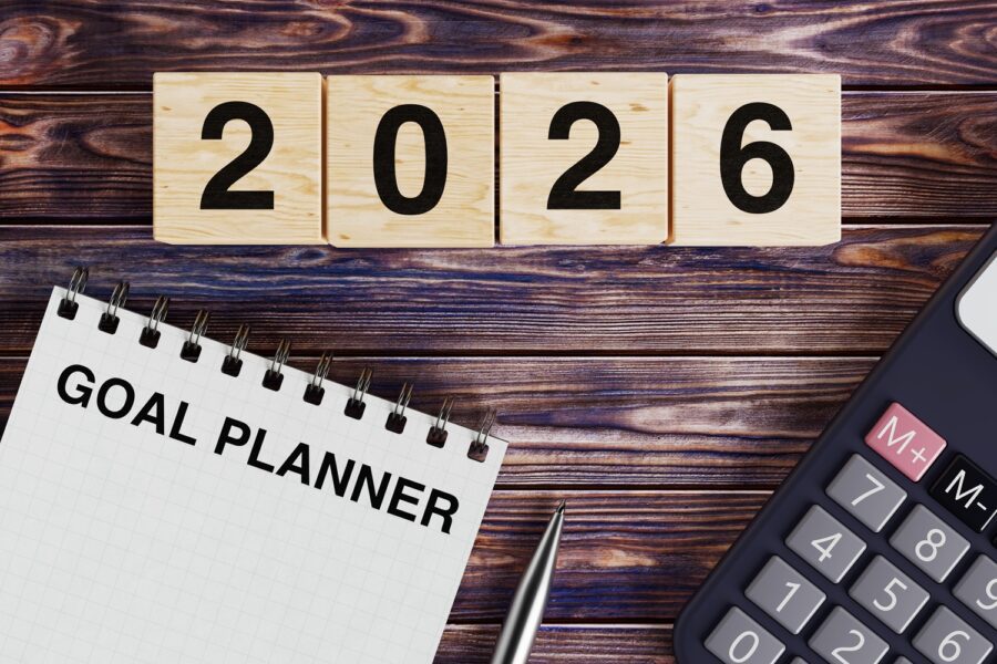 Planning and productivity concept wooden blocks showing 2026 with a goal planner notebook, pen, and calculator