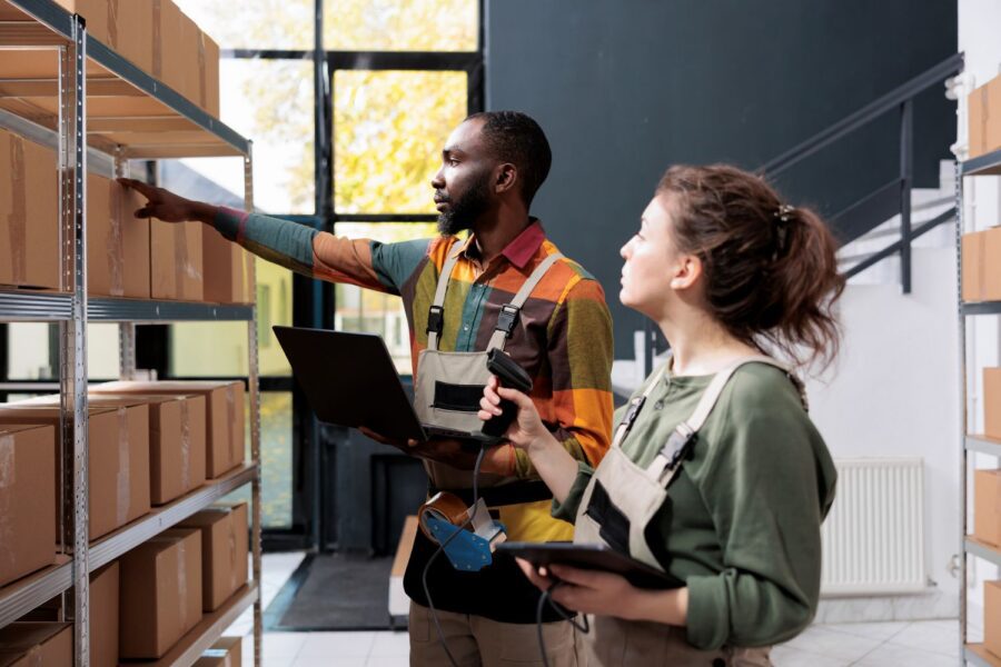 Photograph of two warehouse workers organising and scanning boxes on metal shelving.