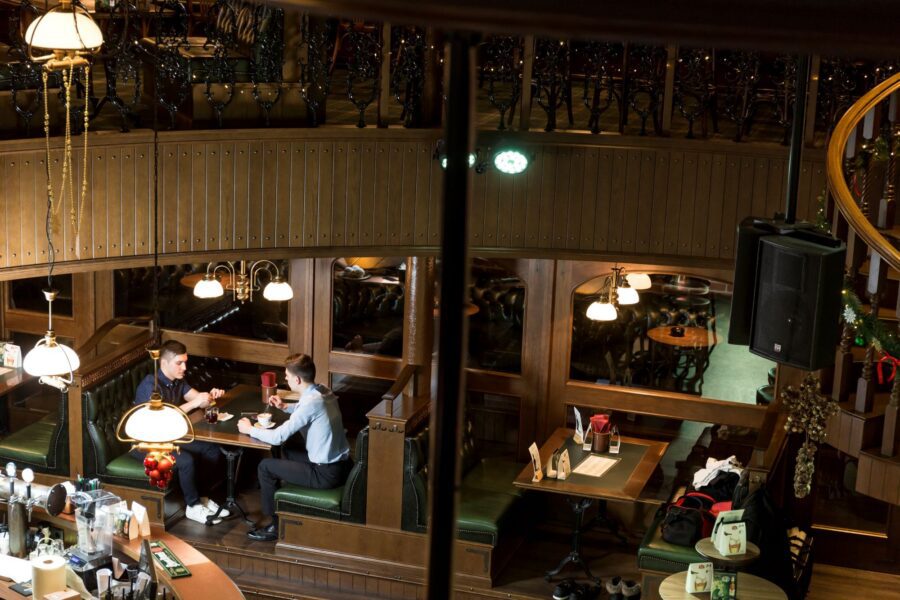 Photograph of two people sitting and talking at a booth in a cosy, wood-panelled restaurant with very few customers.